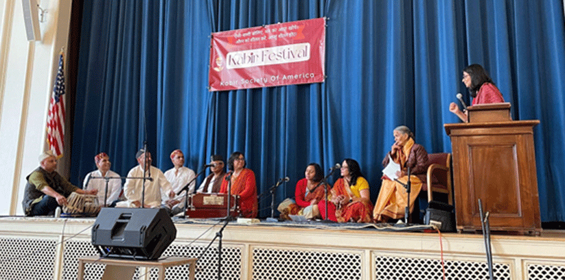 Event emcee Sangeeta Prasad introduces the Uttarakhandis of New England, who sang well-known dohas in a folksy cadence reminiscent of the style popular in the pahaRi (mountainous) regions of Uttarakhand. Photo: S. Ali Rizvi. 