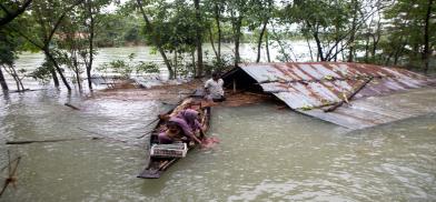A family flees a flood-affected area by boat in Sylhet, Bangladesh, June 2022. This year’s flooding has been worsened by unusual wind patterns linked to climate change, experts say (Image: Alamy)