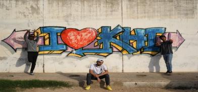 Pakistani rap group KG Stans members (L-R) MC Bablay, MC Affo and Shobi posing near graffiti art in Karachi’s Gizri neighborhood. Photo via Saba Karim Khan / Zayer Films.