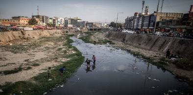 Boys race to fish a plastic bottle out of the heavily polluted and littered Kabul River in Kabul, Afghanistan, in September 2021. The bottles can be sold on for recycling for small amounts of money. (Image: Oliver Weiken / Alamy)